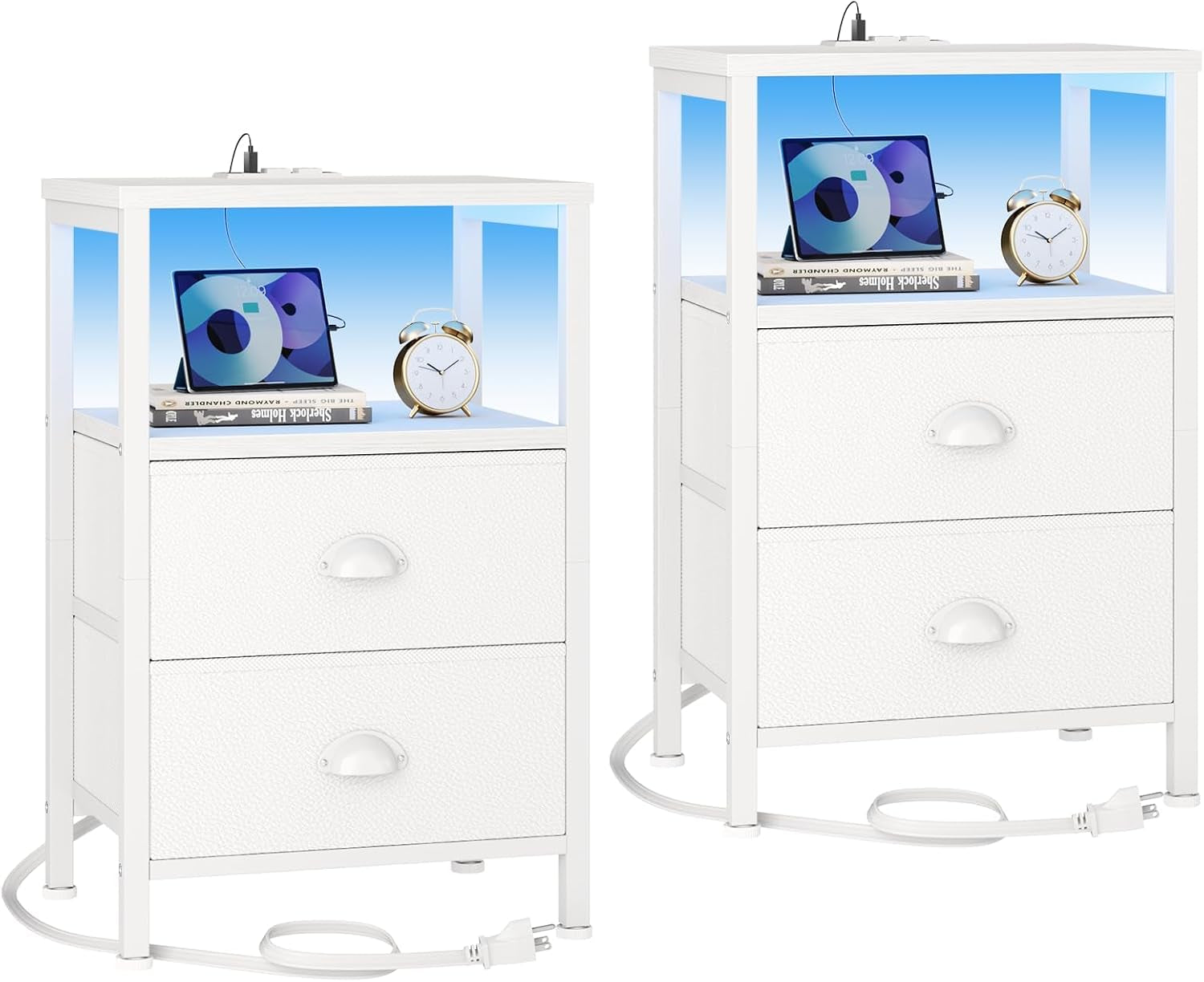 Pair of white bedside tables with two fabric-front drawers, open shelf and power cord visible