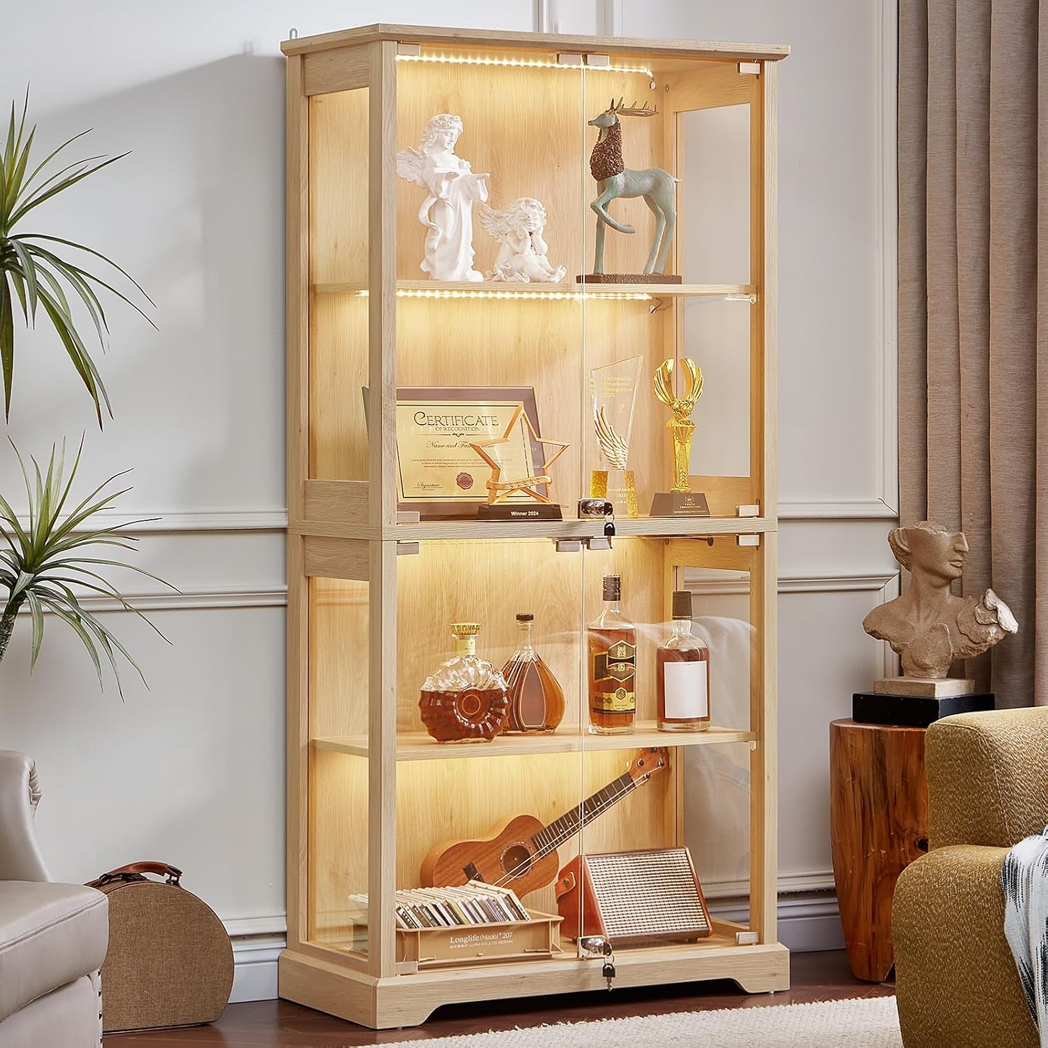Tall walnut-finish glass display cabinet lit inside, staged in a living room with trophies and decor