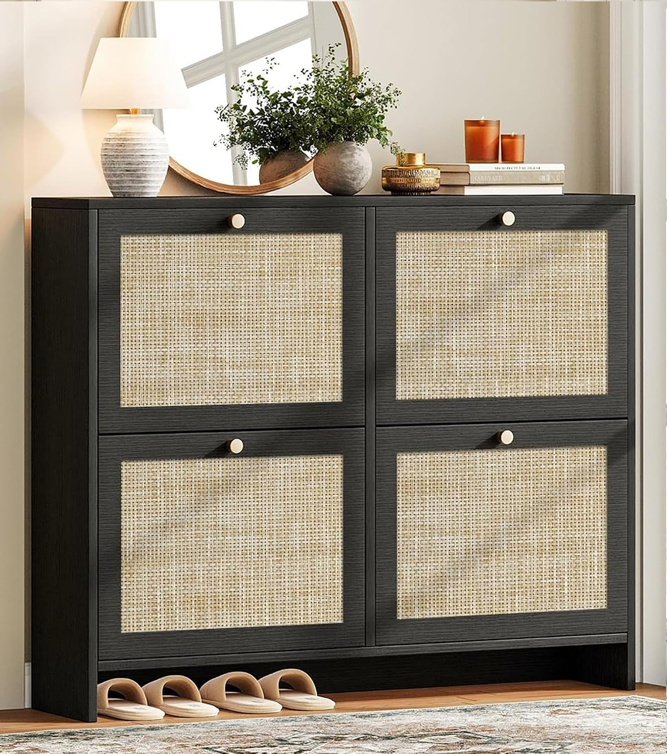 Front view of a black freestanding shoe cabinet with four square rattan panels and four round knobs, slippers below.