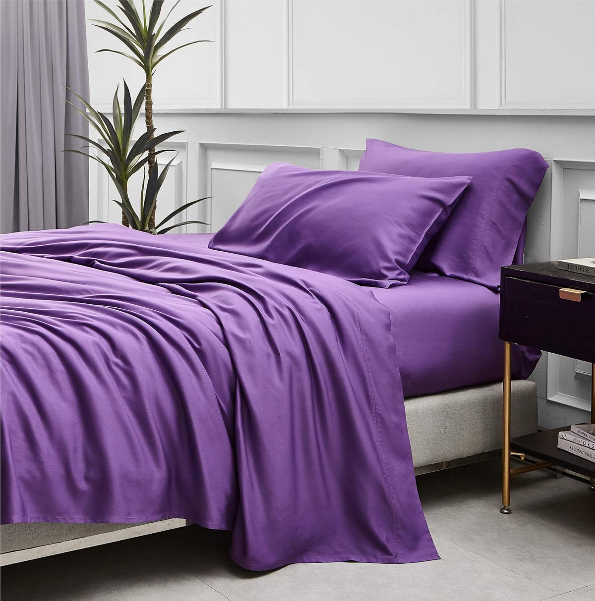Close view of a made bed with smooth purple flat sheet and two matching pillowcases.