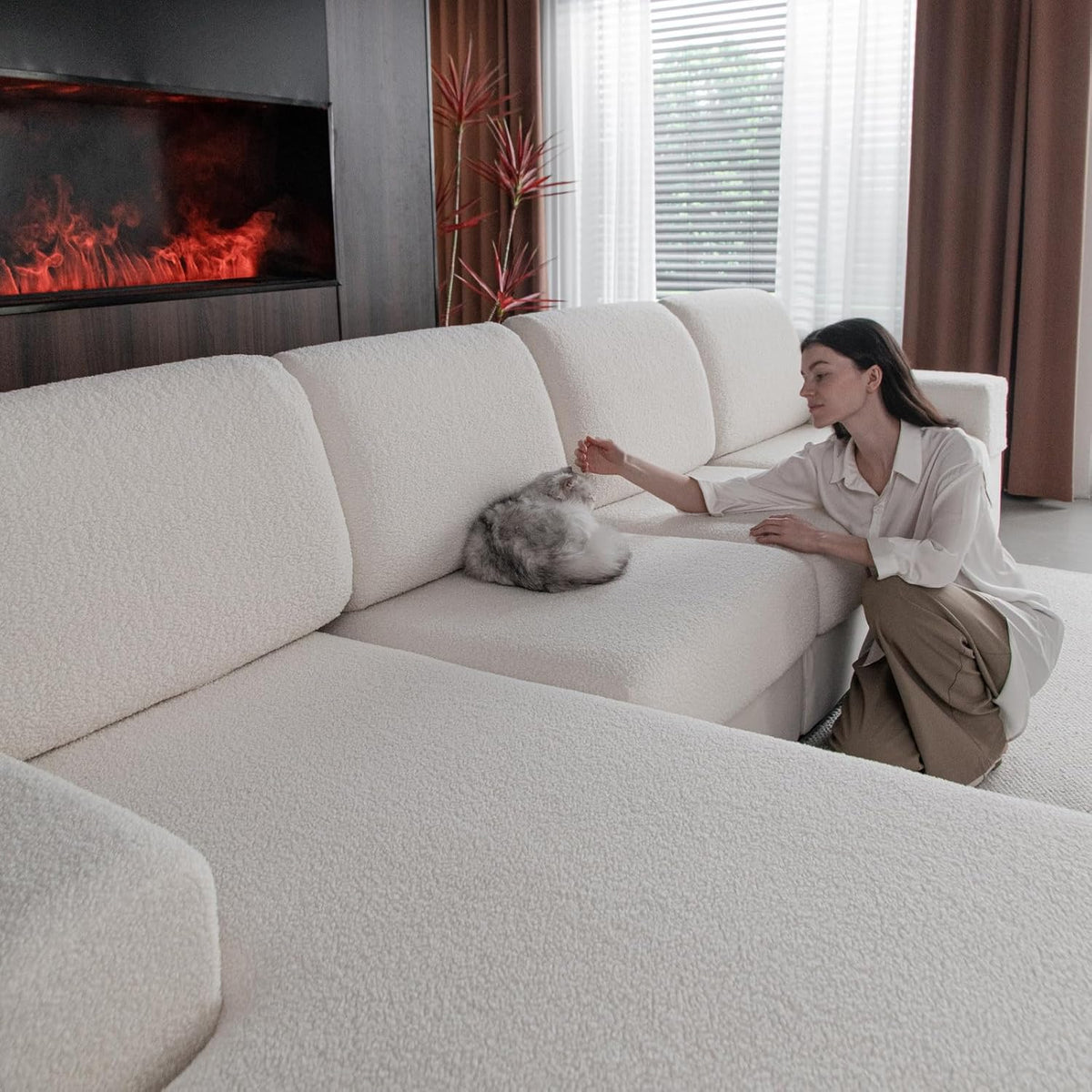 Side view of a woman kneeling beside a covered sofa seat while a gray cat sits on the textured cushion cover