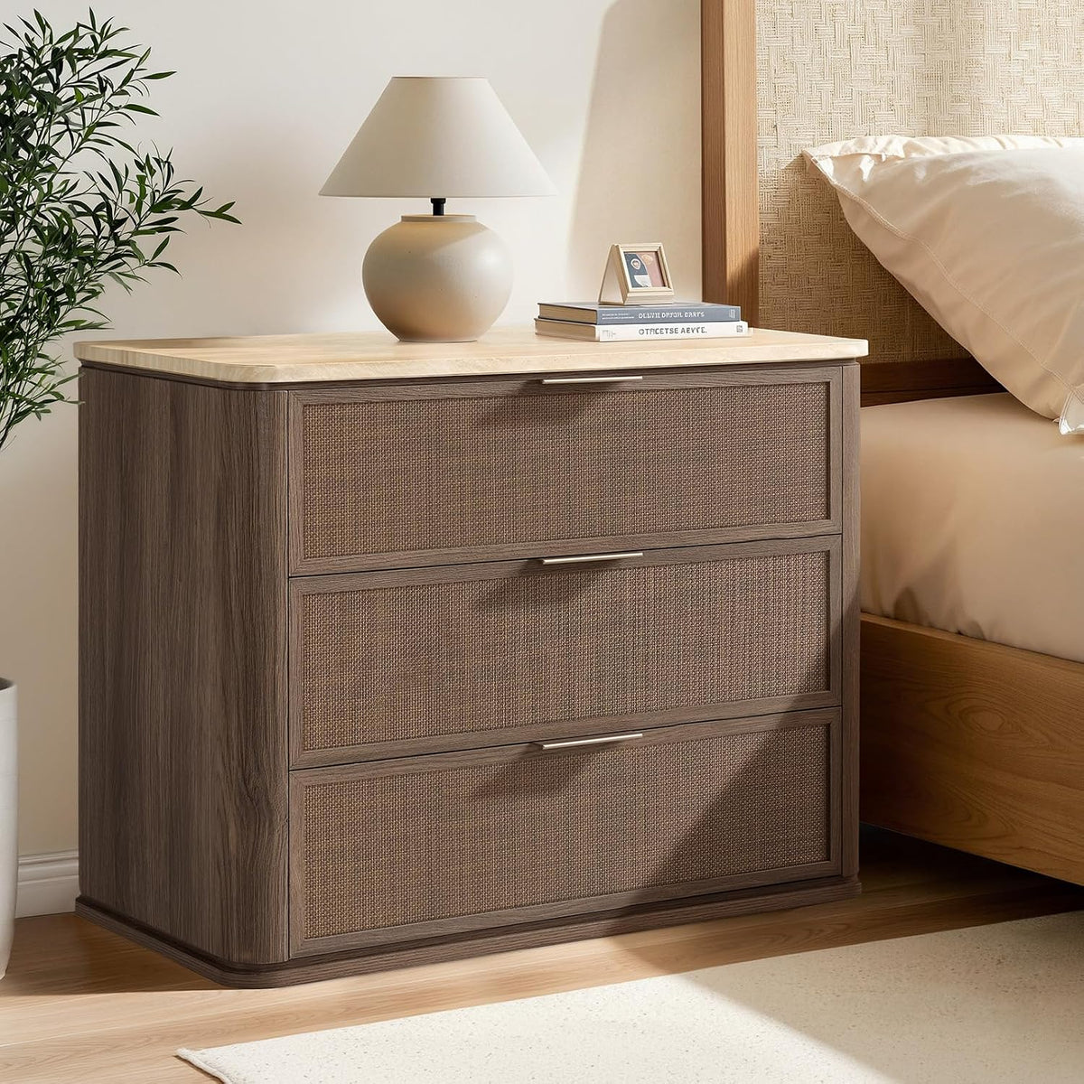 Dark oak three-drawer nightstand with faux marble top beside a bed, lamp on top.