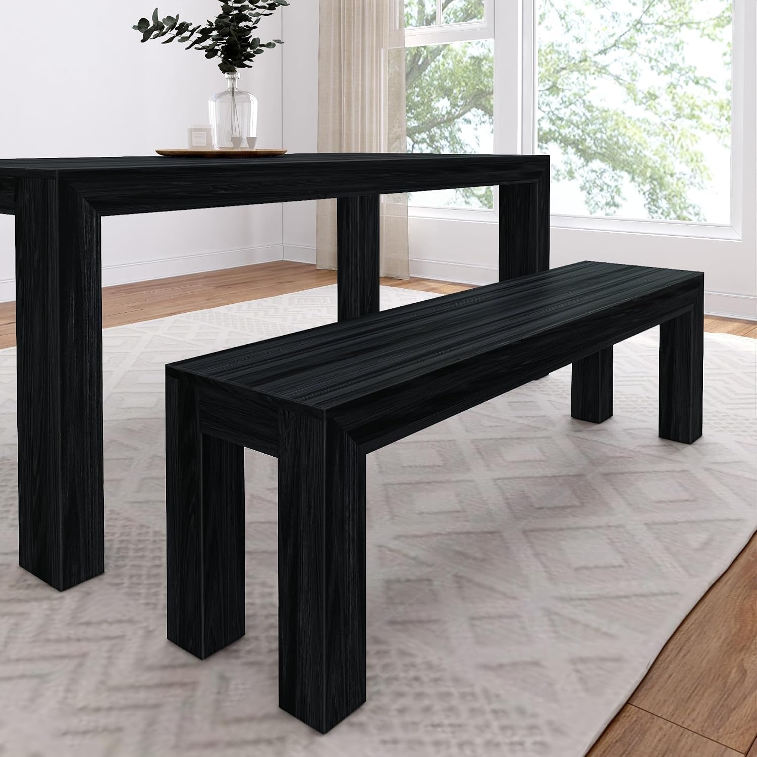 Long black wood dining table paired with a matching bench on a patterned rug