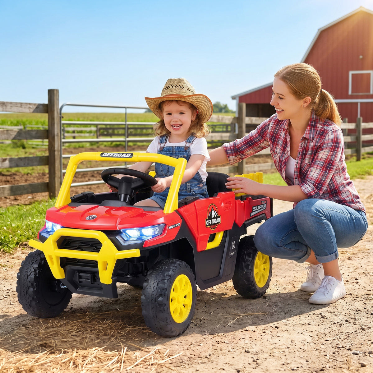 A child sits in a red ride-on truck as a woman kneels beside it on a farm.