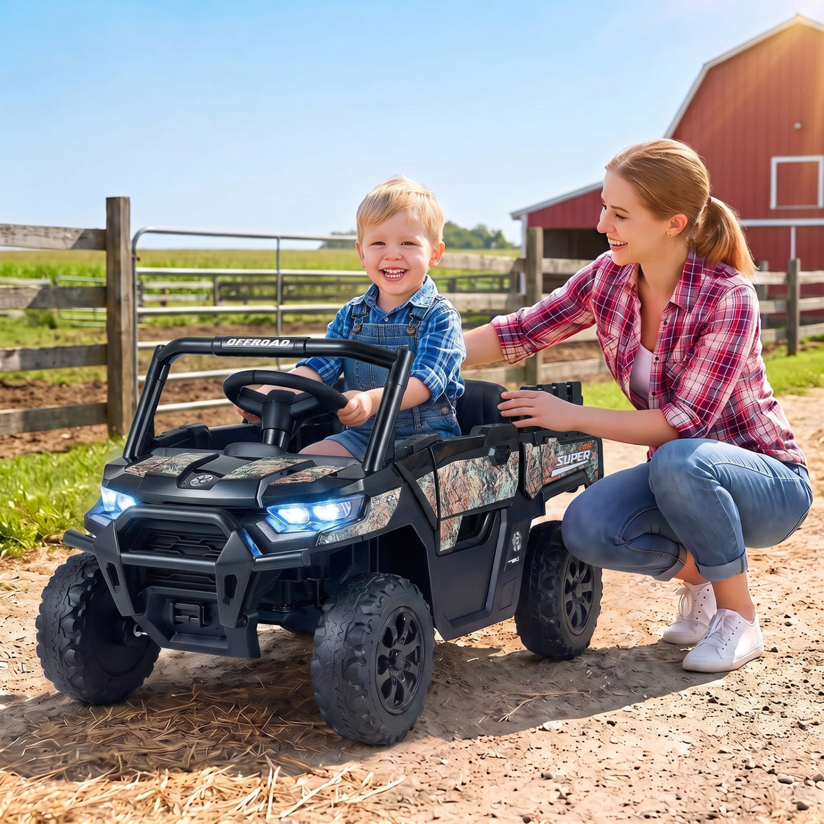 A child sits in a black ride-on truck while an adult kneels beside it on a farm path.