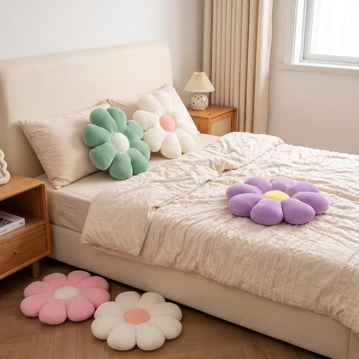 Mint green and cream daisy pillows styled on a bed with a purple daisy pillow on the comforter, bedroom view