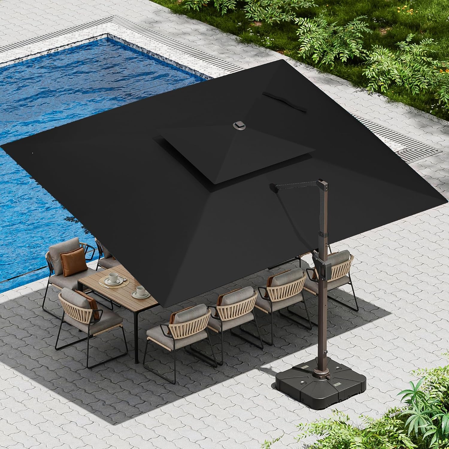 Aerial view of a black square cantilever umbrella covering an outdoor dining set near a pool.