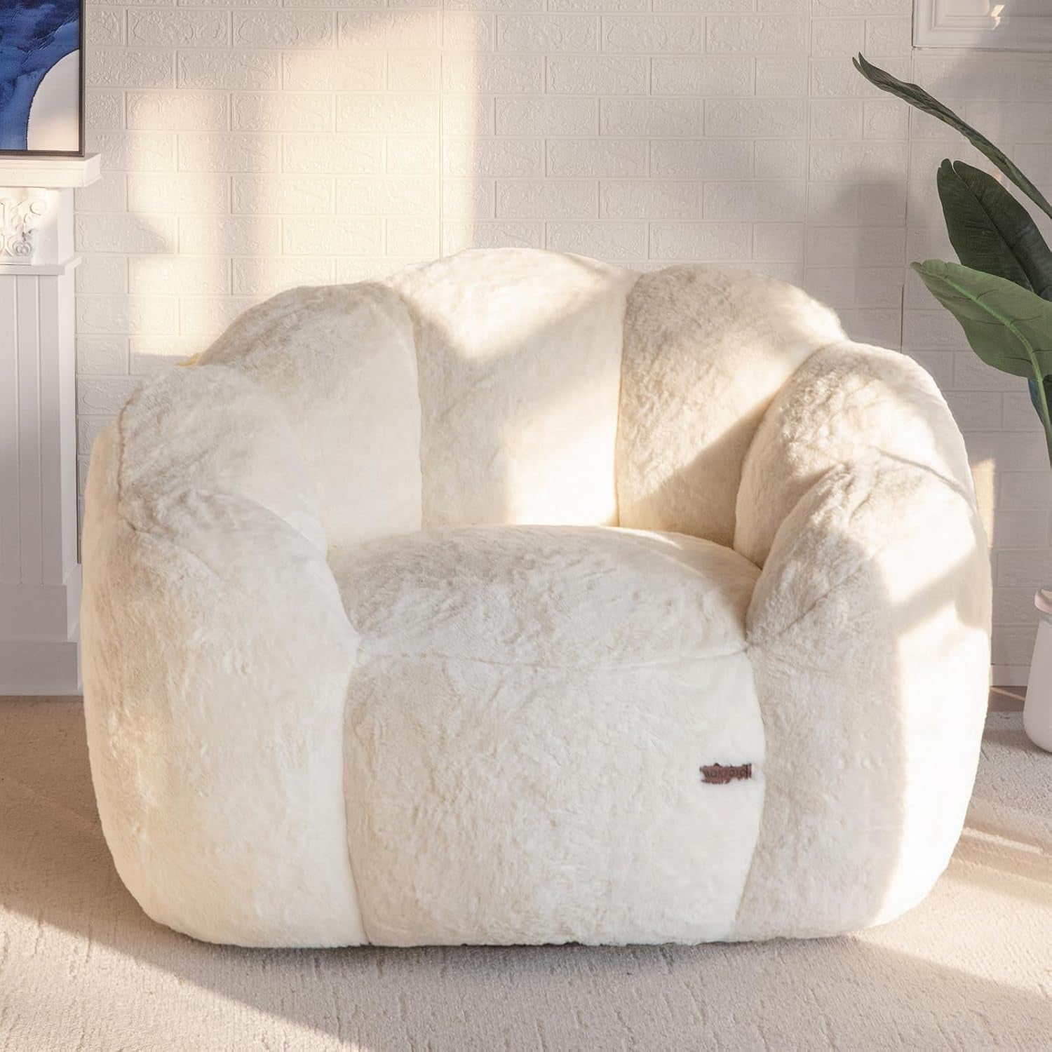 Plush floral-shaped bean bag chair in creamy ivory shown centered on a light carpet with soft sunlight.