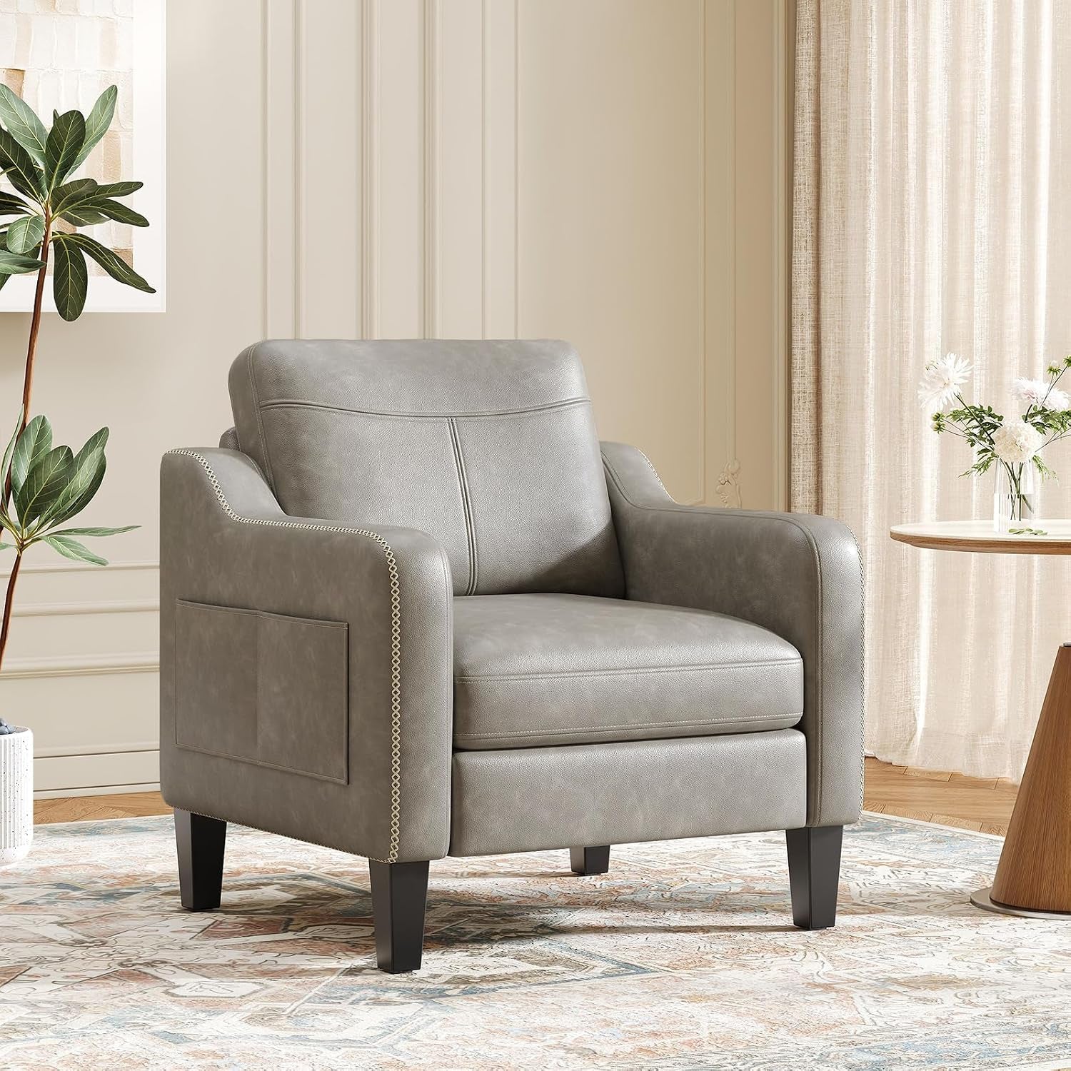 Cool gray faux leather accent chair with stitched back and black legs beside a side table