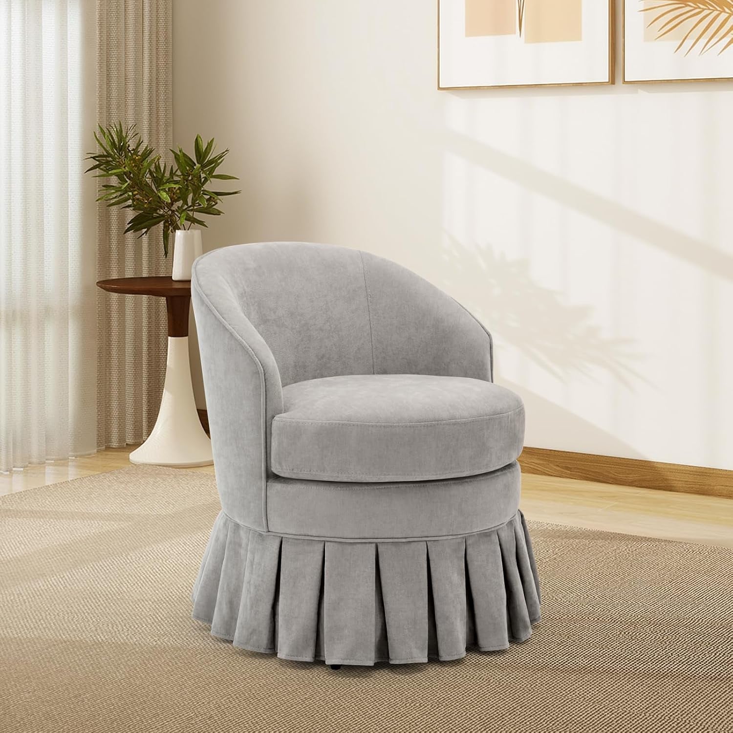 Single light gray upholstered barrel accent chair with pleated skirt shown in a sunlit corner.