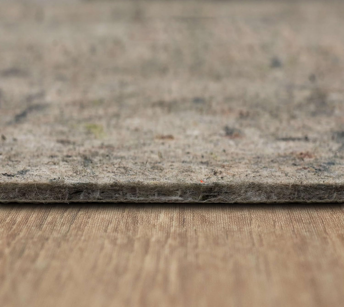 Low-angle shot of the pad edge resting on a beige woven surface, showing compressed fiber layers.