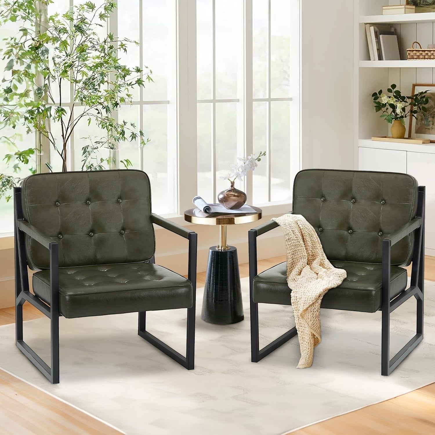 Two olive-green tufted accent chairs with black frames beside a gold-and-black side table in a bright room