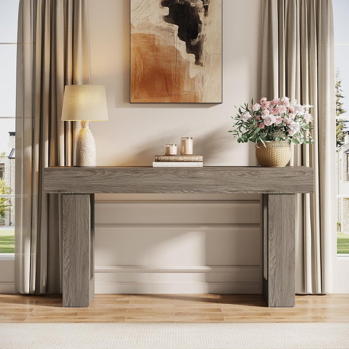 Centered front view of grey console under abstract art, lamp at left and woven flower pot at right.