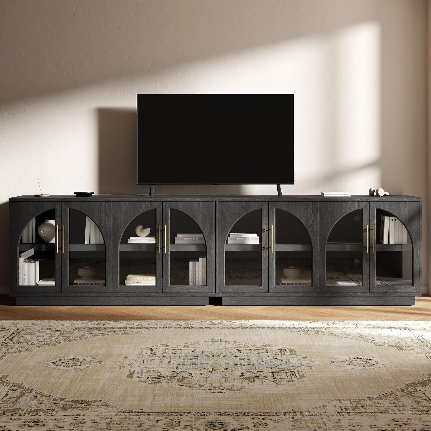Dark gray buffet with arched glass-front doors showing interior shelves and decor under a TV.