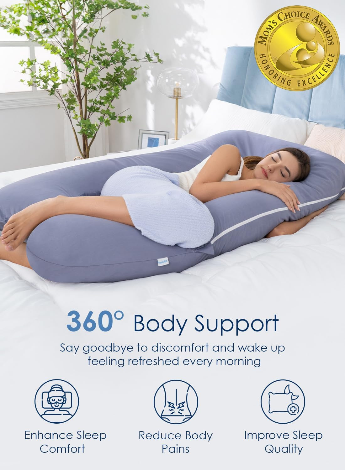 Full-length lifestyle view of a blue U-shaped pregnancy pillow on a bed with a woman sleeping inside
