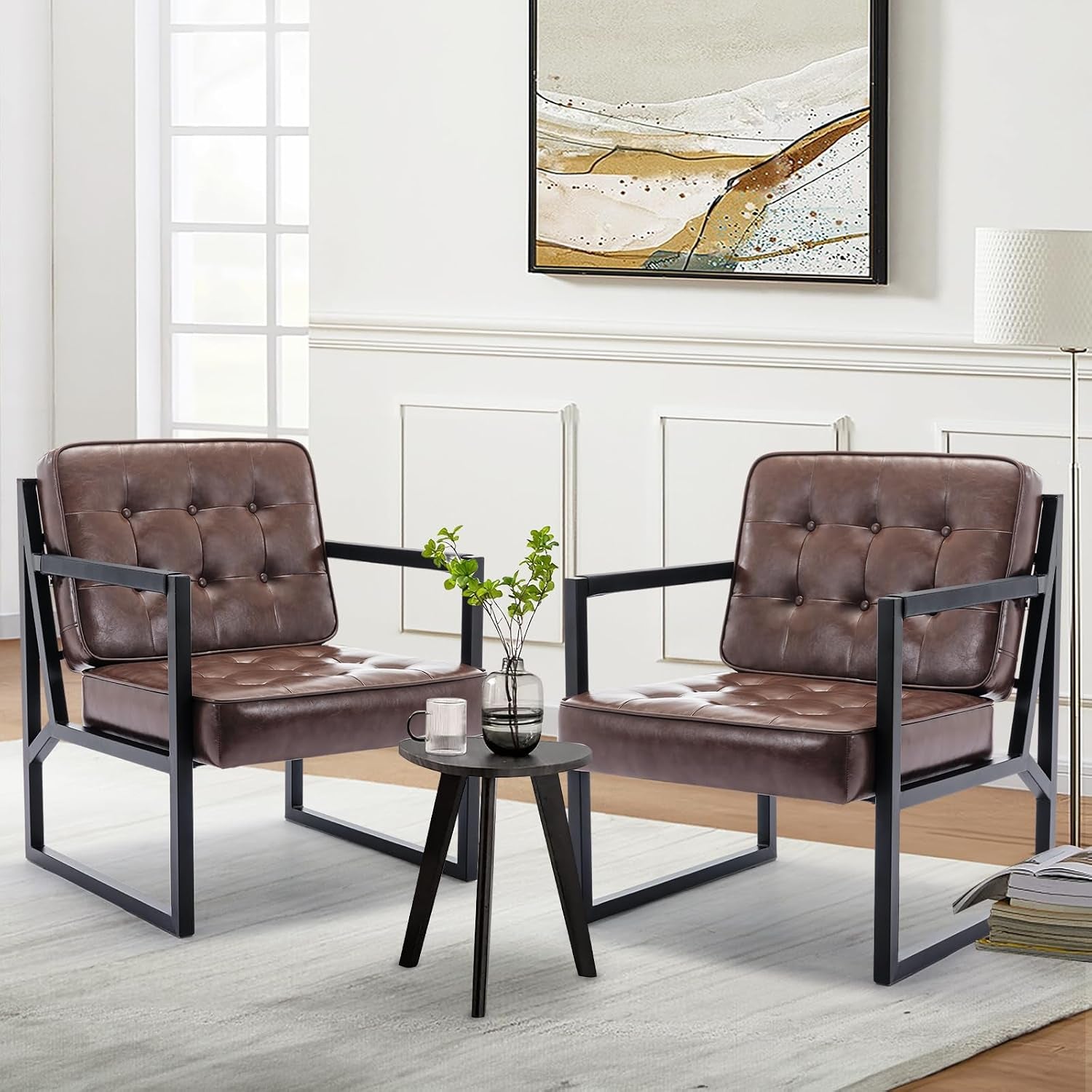Pair of brown tufted faux-leather chairs with black metal frames flanking a small round black side table