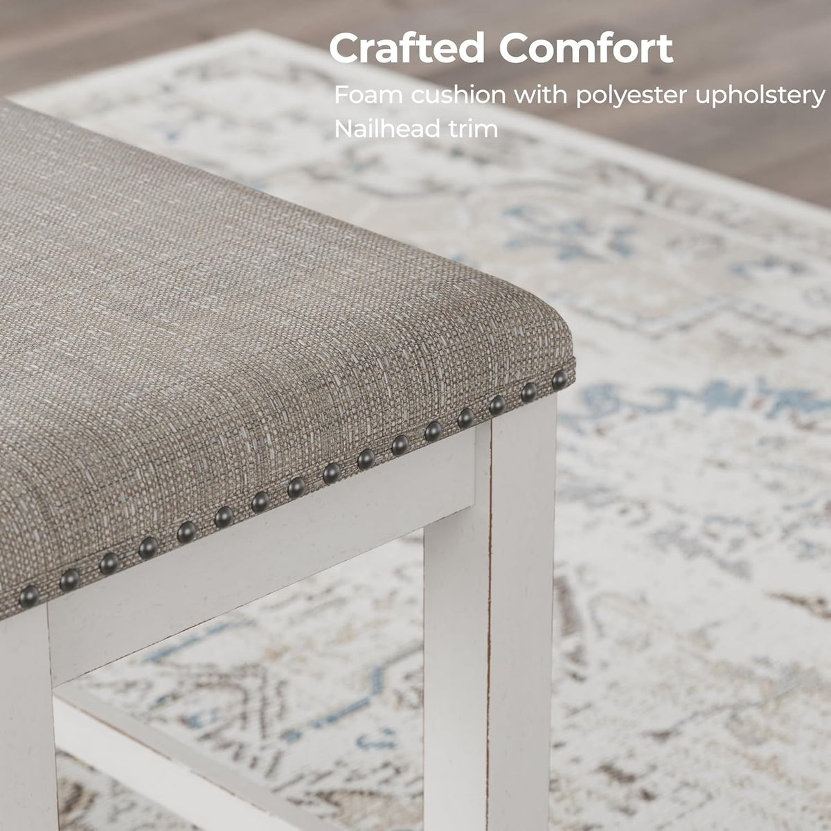Close-up of light gray polyester upholstered seat corner with metal nailhead trim and antiqued white frame