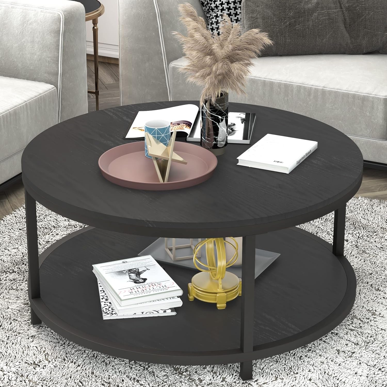 Round two-tier coffee table in dark/black finish with decorative tray, vase and books on top