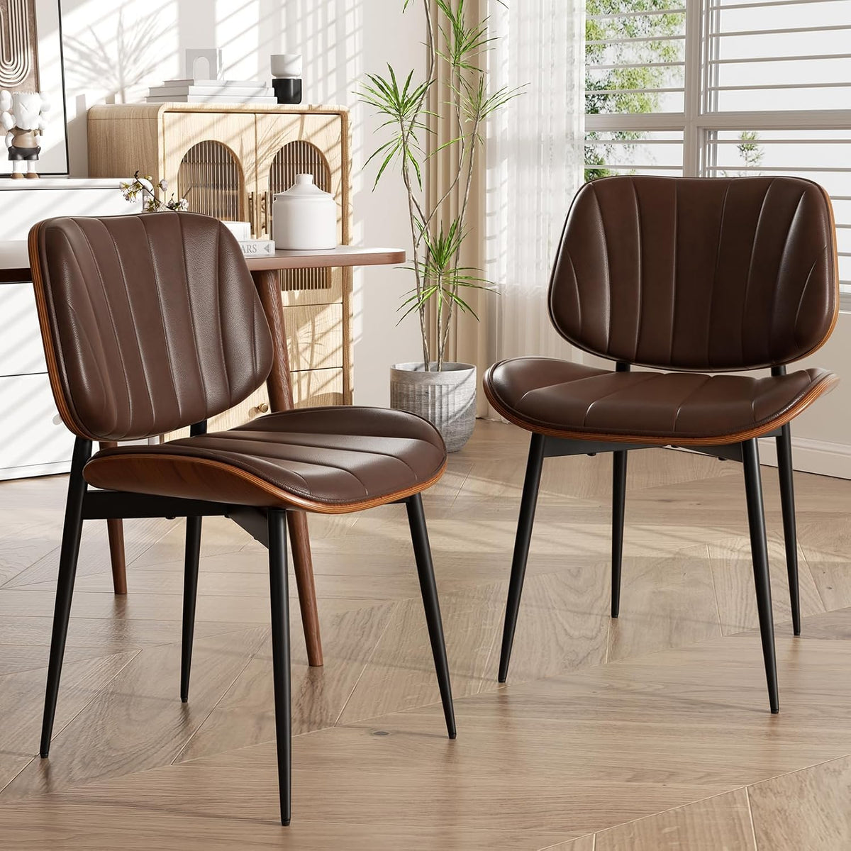 Close-up of two chairs showing curved walnut backs, padded seats and black metal legs.
