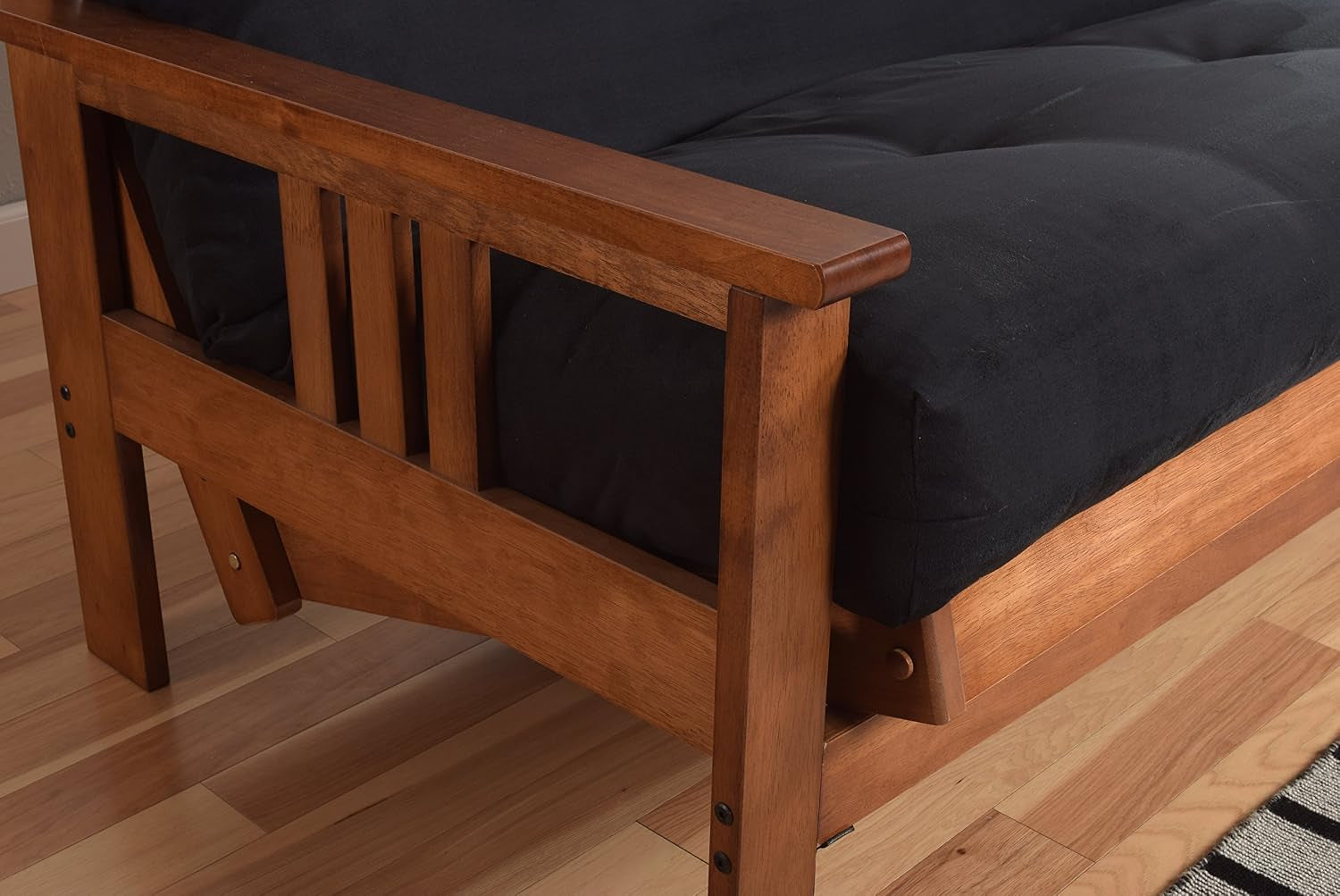 Corner close-up of cushioned charcoal seat and rounded wooden armrest on a hardwood frame
