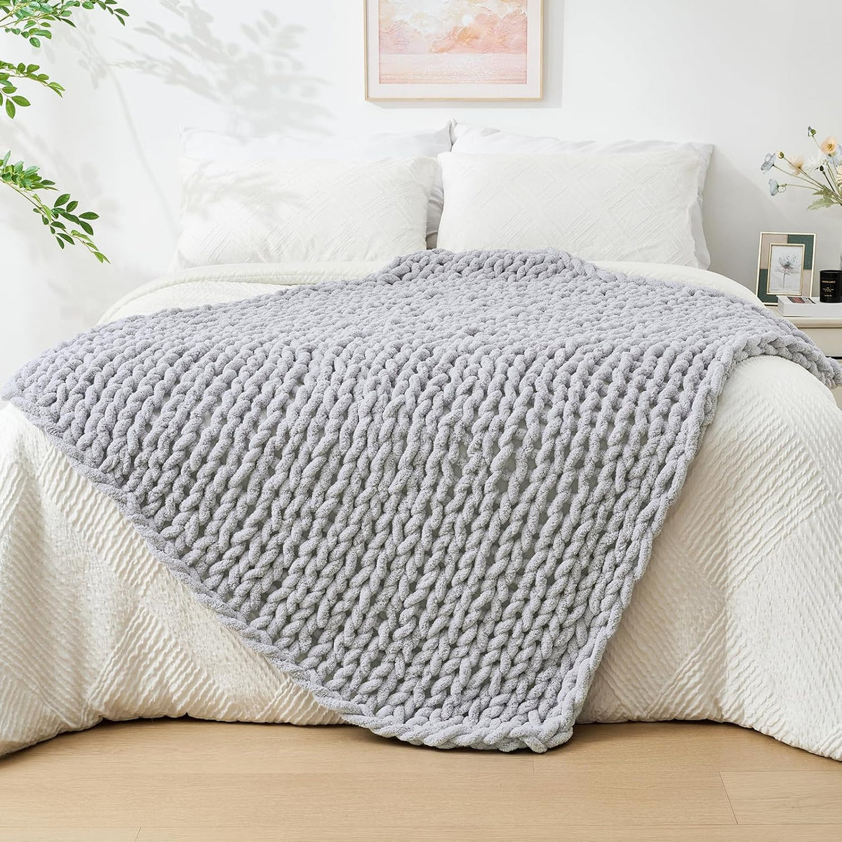 Light gray chunky knit throw spread flat over a made bed, showing braided rows