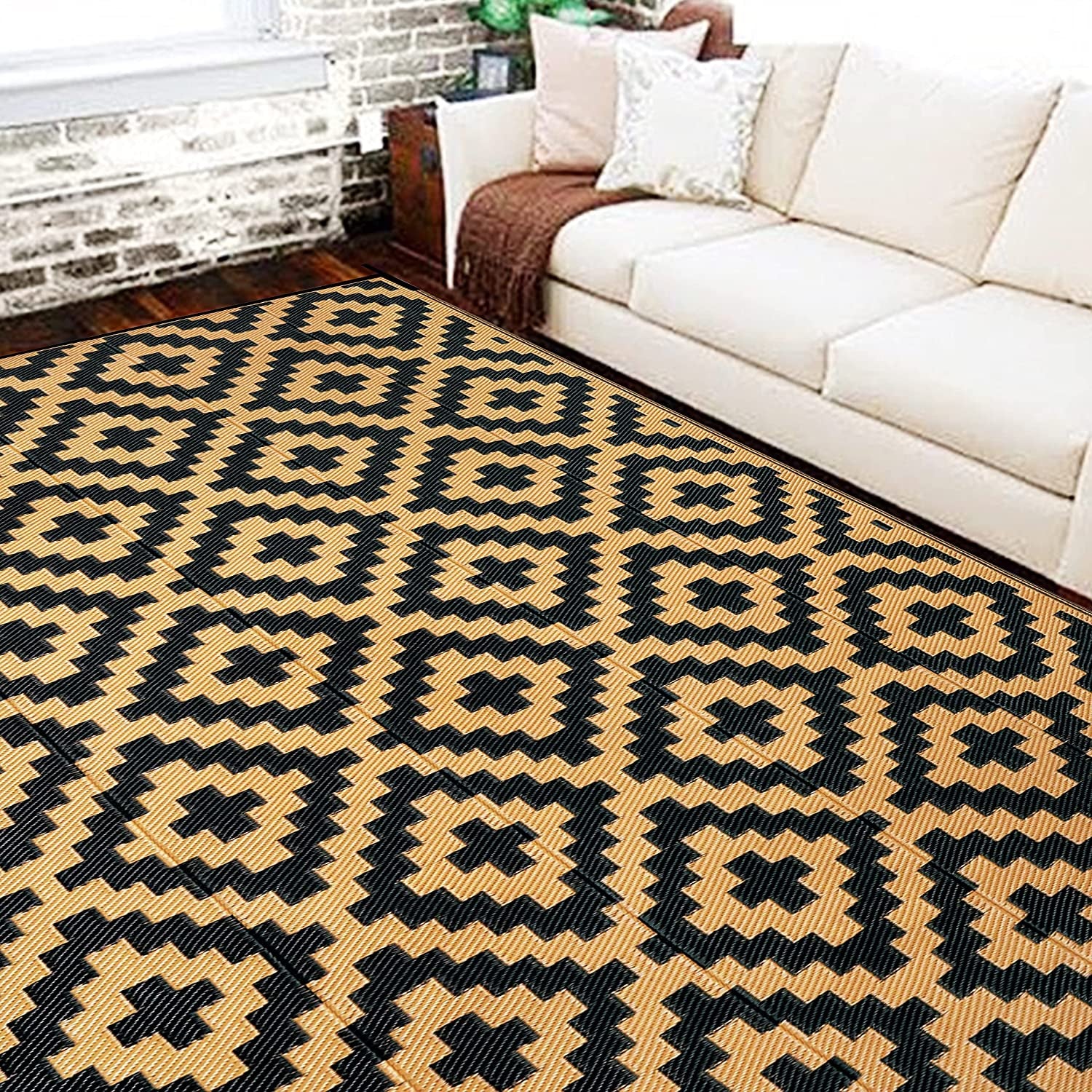 Living room view of a tan-and-black geometric rug placed in front of a cream sofa.
