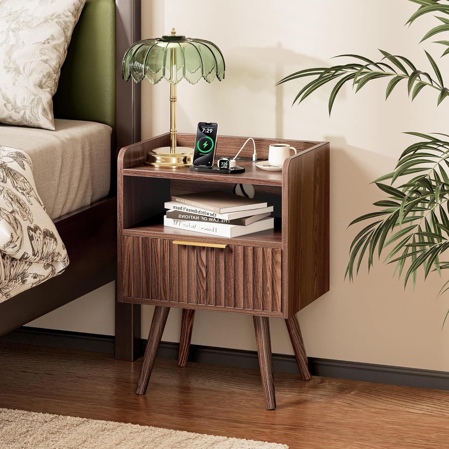 Walnut nightstand placed beside bed showing open shelf, drawer and raised edge tabletop