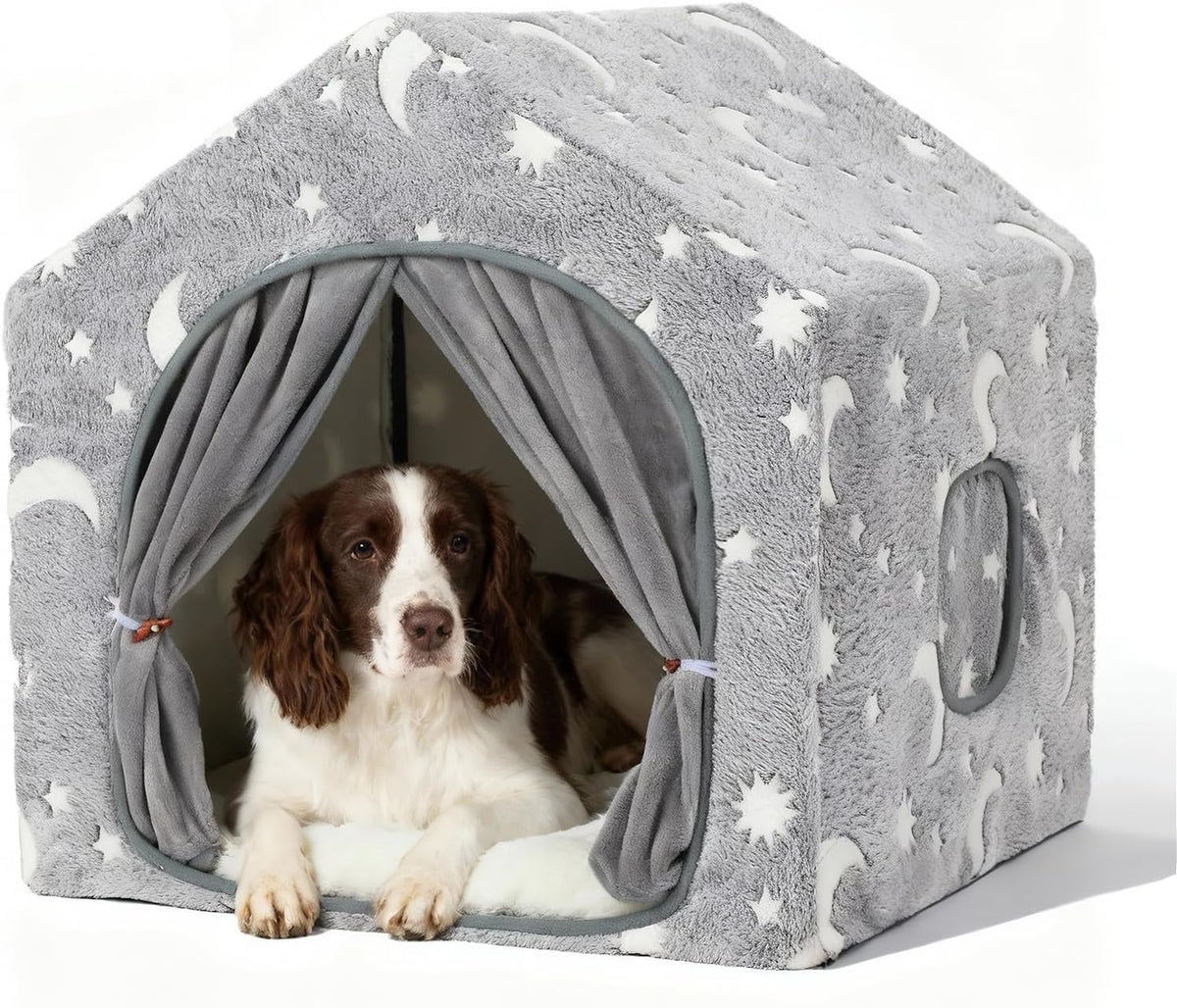 Low-angle three-quarter view of the grey plush house with a brown-and-white dog resting on the cushion and moon pattern