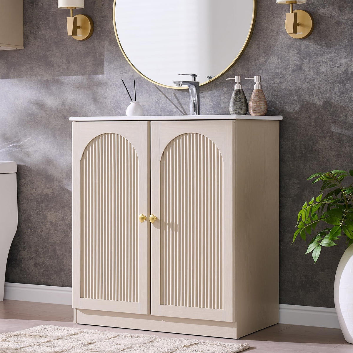 Front view of a freestanding natural oak bathroom vanity with arched fluted double doors, white sink top and gold knobs.