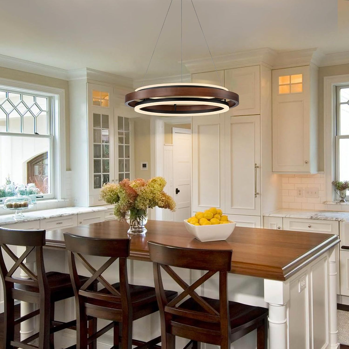 Walnut-color round chandelier suspended above a kitchen island with wooden counter and bar stools