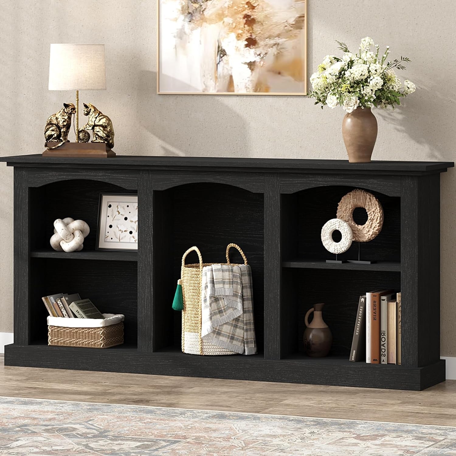 Front view of the console table in a black finish with shelves staged with baskets and books.