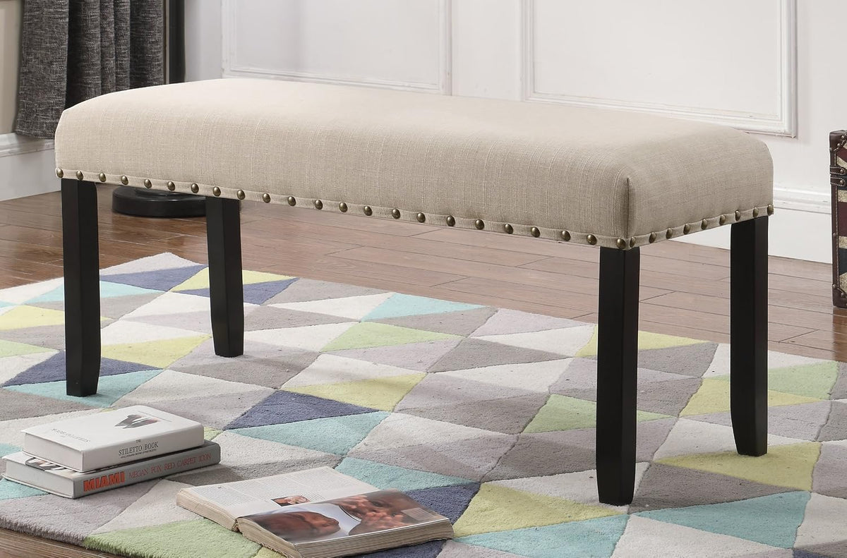 Angled front view of tan upholstered dining bench on hardwood floor and patterned rug showing full seat and legs