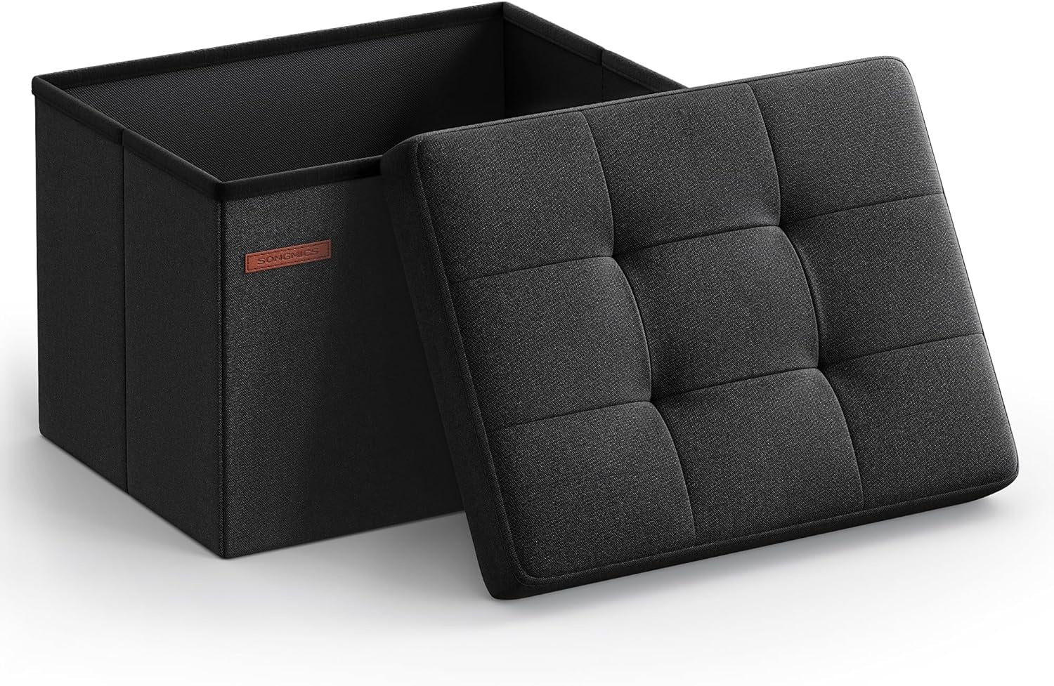 Three-quarter view of a dark gray fabric folding storage ottoman with tufted lid propped against the open interior