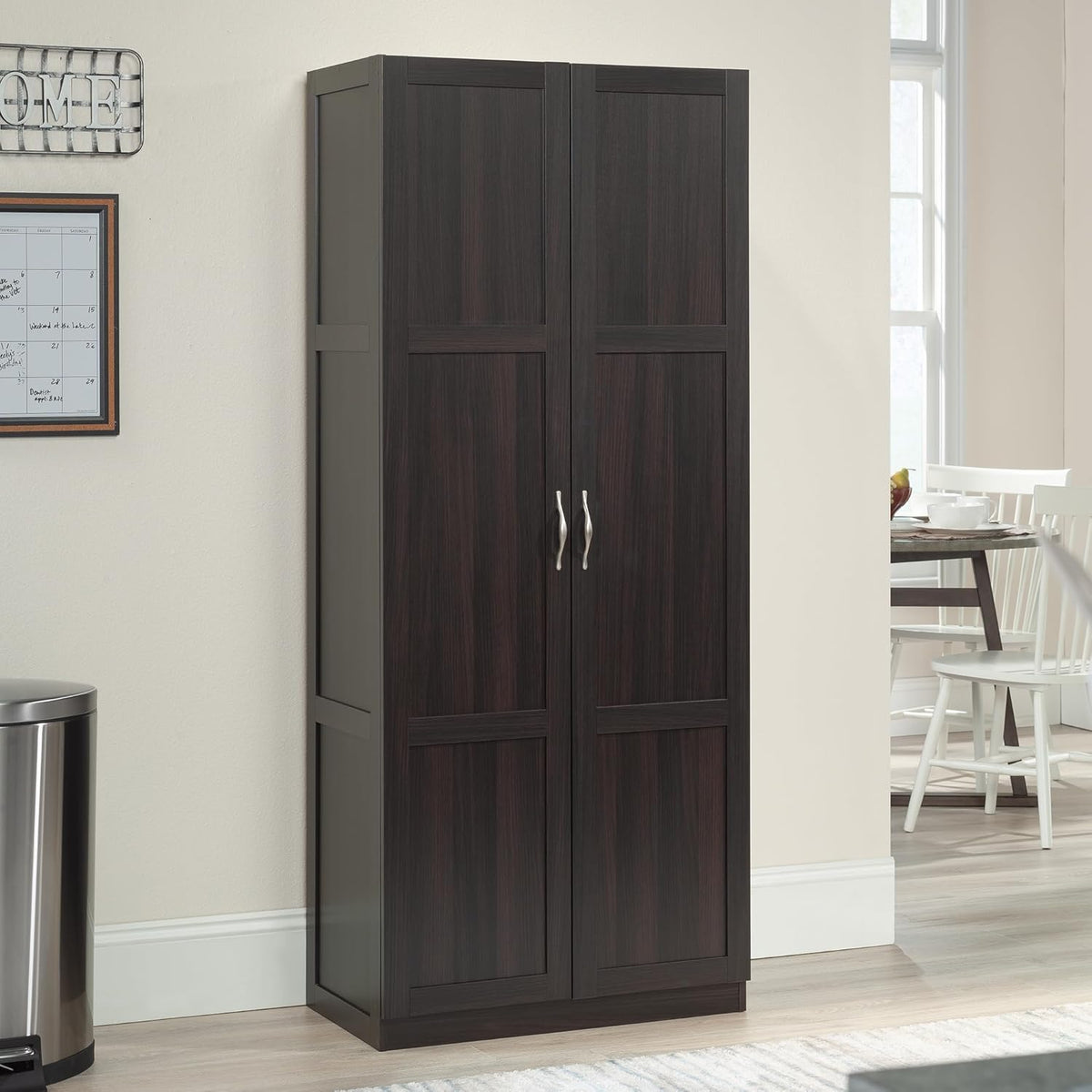 Dark-finish two-door storage cabinet staged in a bright kitchen/dining area, angled front view