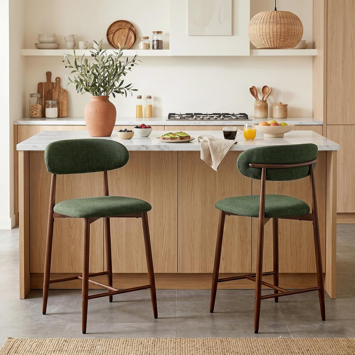 Two green upholstered counter stools side by side in front of a kitchen island with tableware on the countertop.