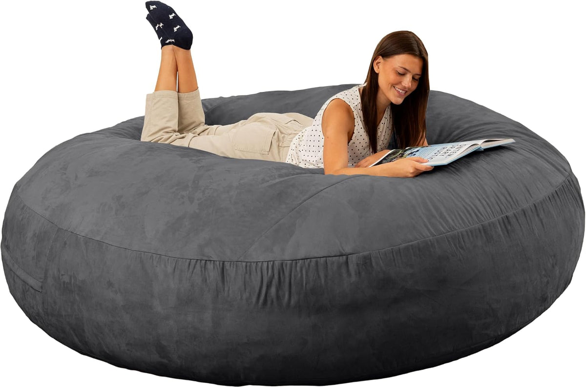 Woman lying on a deep charcoal-gray round bean bag bed reading a magazine