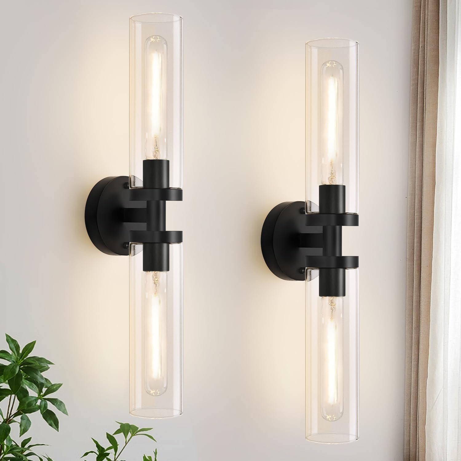 Front view of two identical lit wall sconces with long tubular bulbs inside clear glass cylinders.