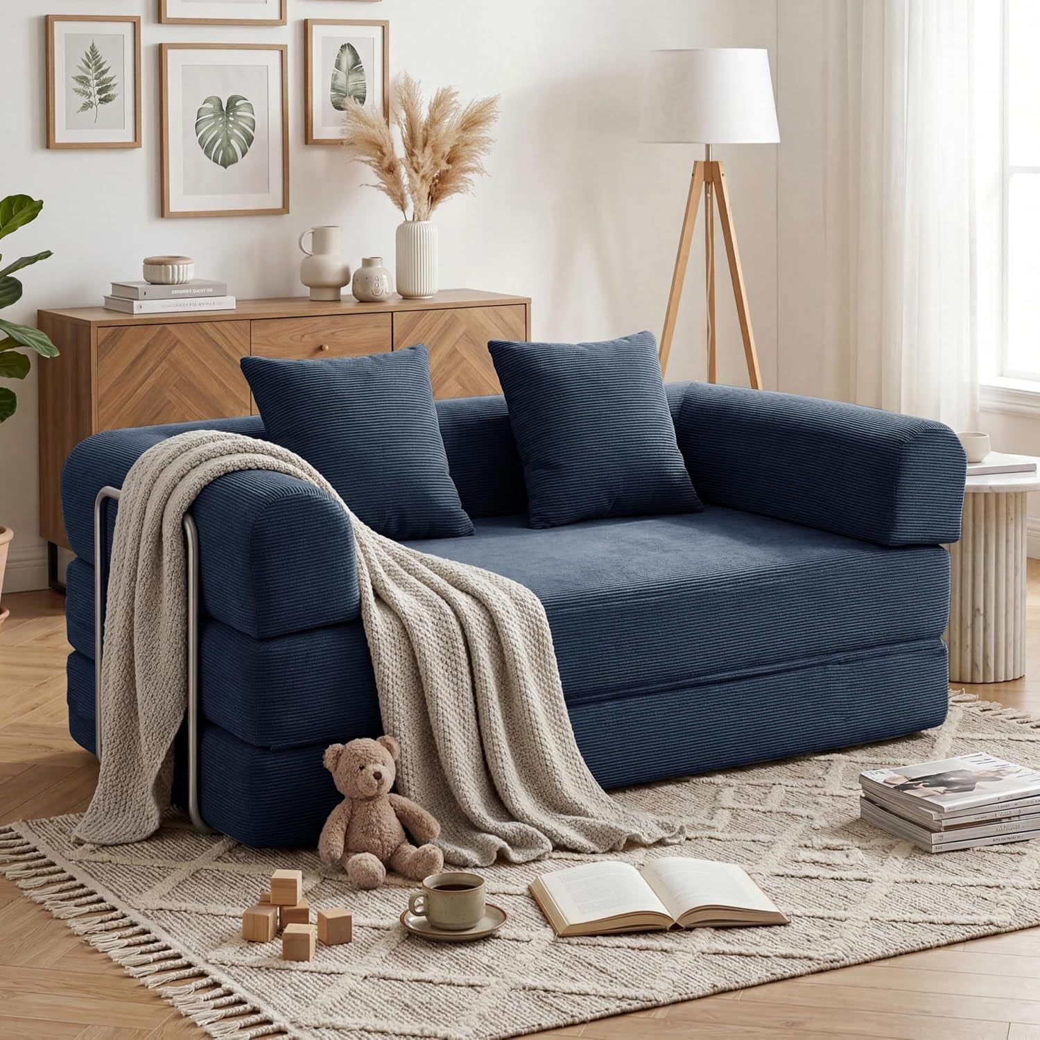 Navy corduroy convertible sofa arranged as a chaise with throw blanket and toys nearby