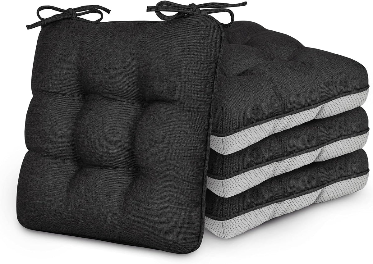 Stack of four dark charcoal tufted chair cushions with ties, front cushion leaning on the pile