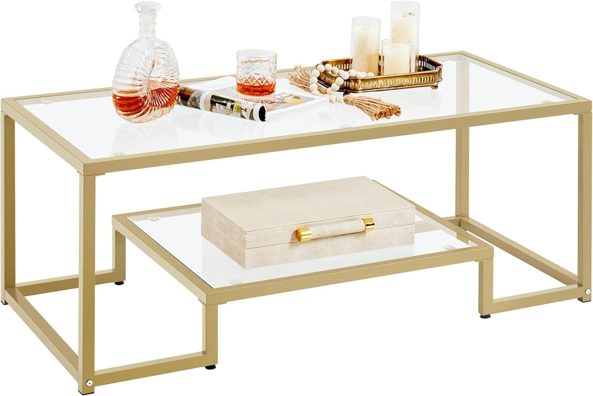 Gold metal-framed glass coffee table angled close-up showing top and lower shelf with decorative items