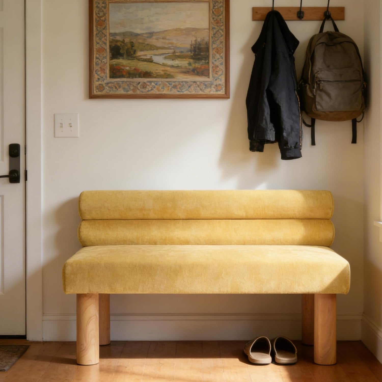Low-backed mustard-yellow upholstered bench with round natural wood legs in an entryway.