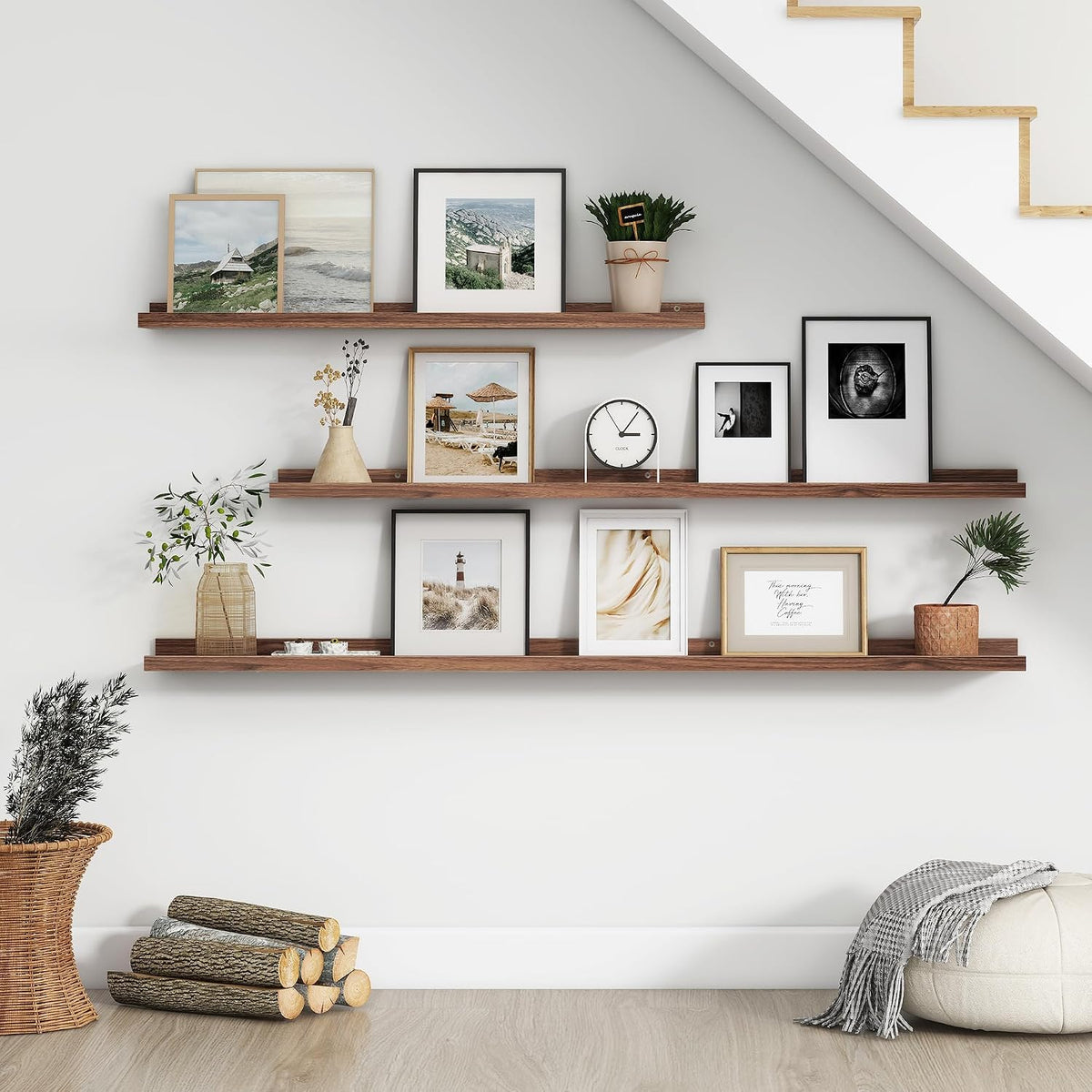Three long dark wood floating ledges mounted on a white wall styled with framed photos, plants and decor.