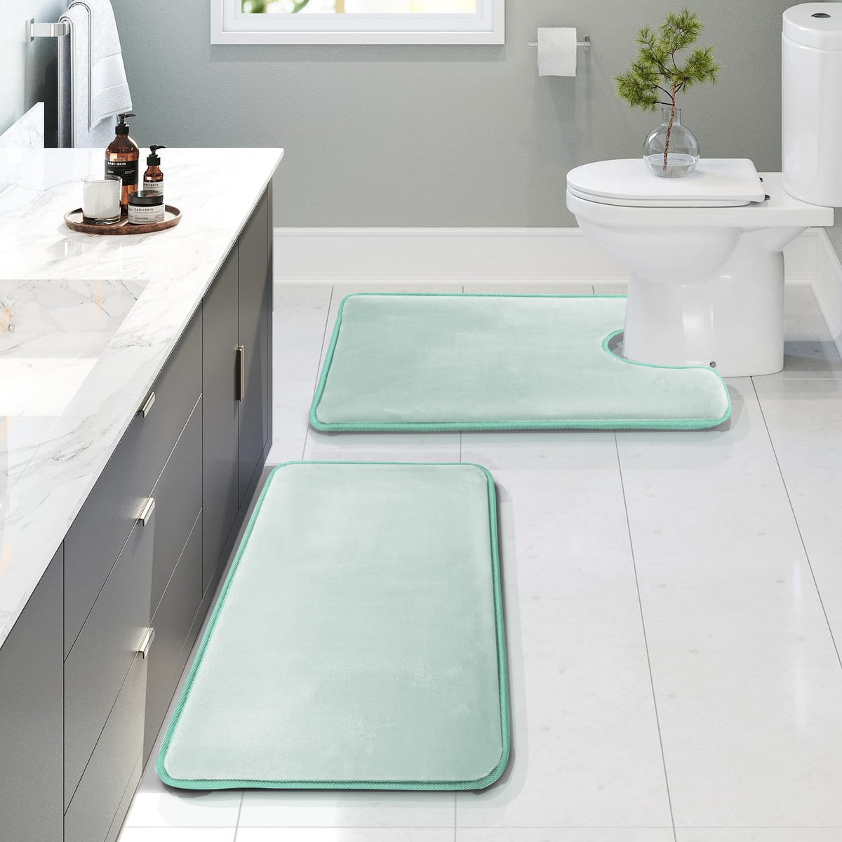 Bathroom scene with two mint-green memory foam rugs, one rectangular runner and one U-shaped toilet rug on white tile