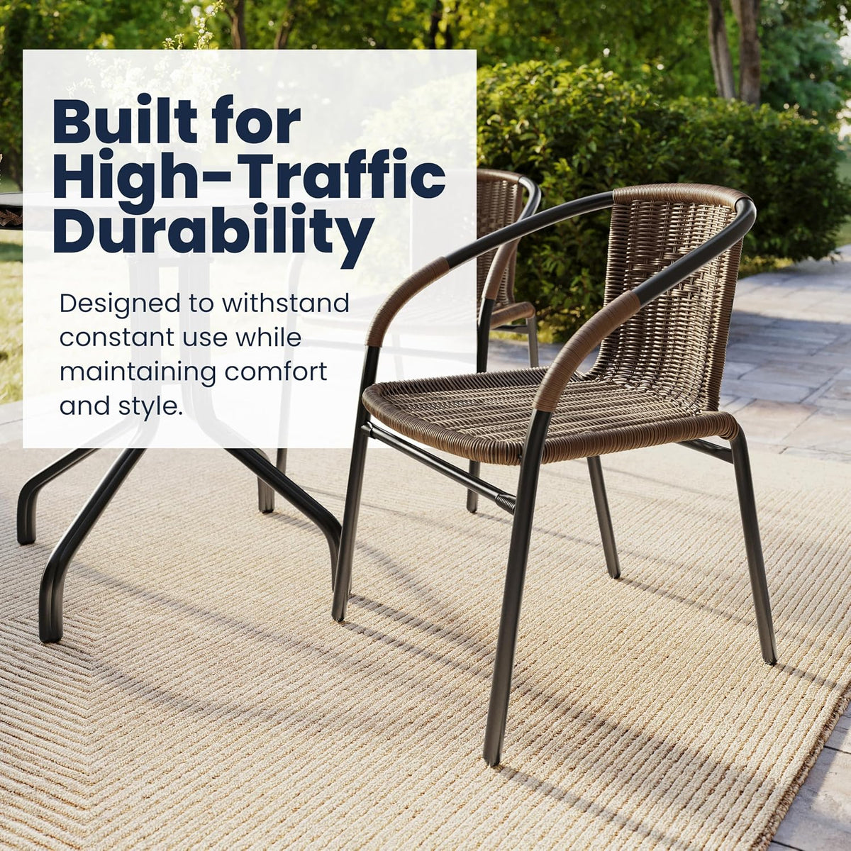 Two brown rattan chairs around a table on a rug outdoors, one chair in foreground and another partially visible
