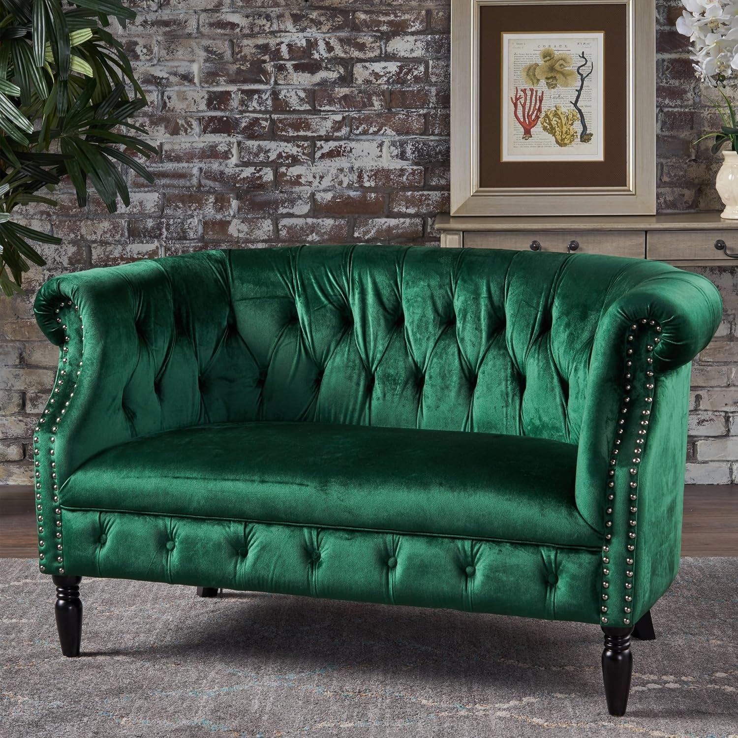 Emerald velvet Chesterfield loveseat angled front view highlighting tufted back and scrolled arms in room