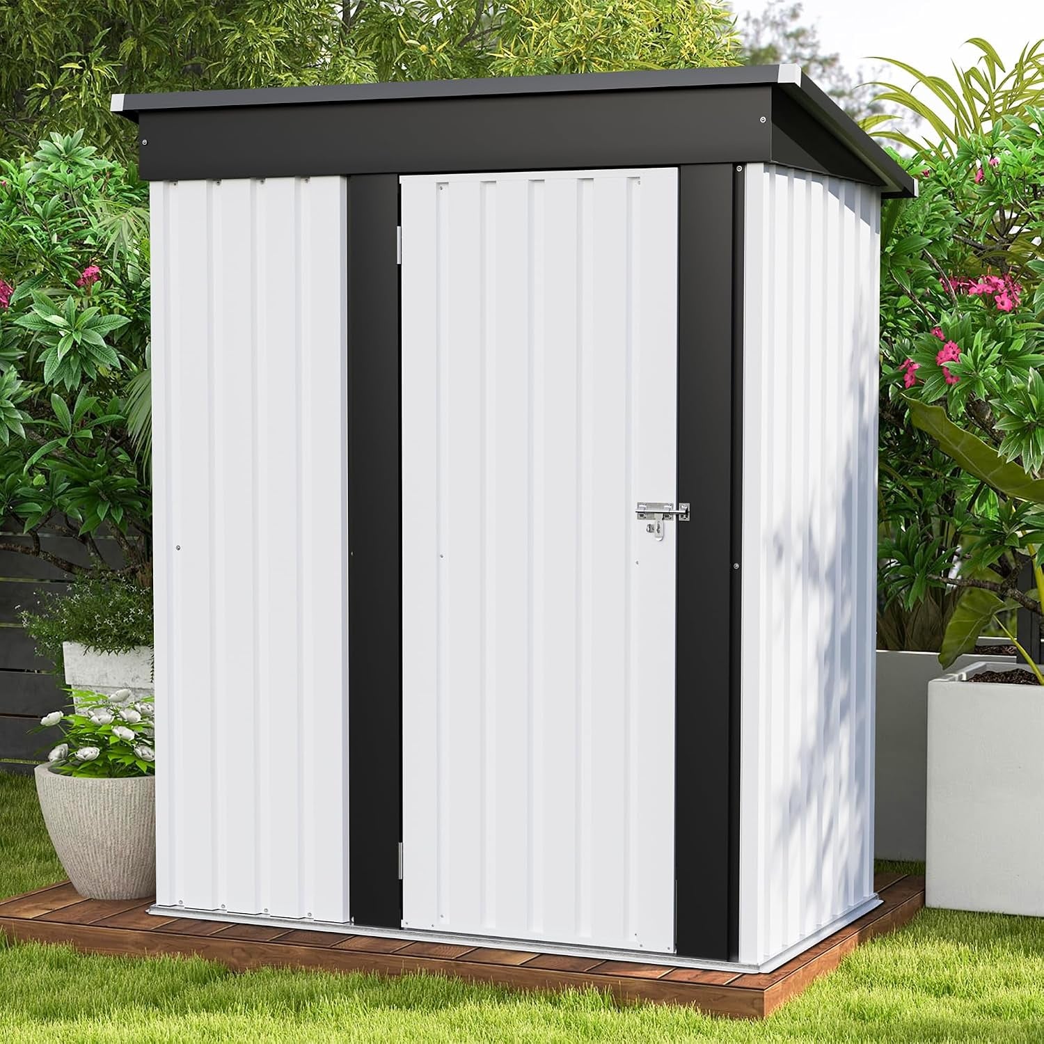 Front view of a small white metal shed with black trim and a padlock latch, placed on a wooden base among plants.
