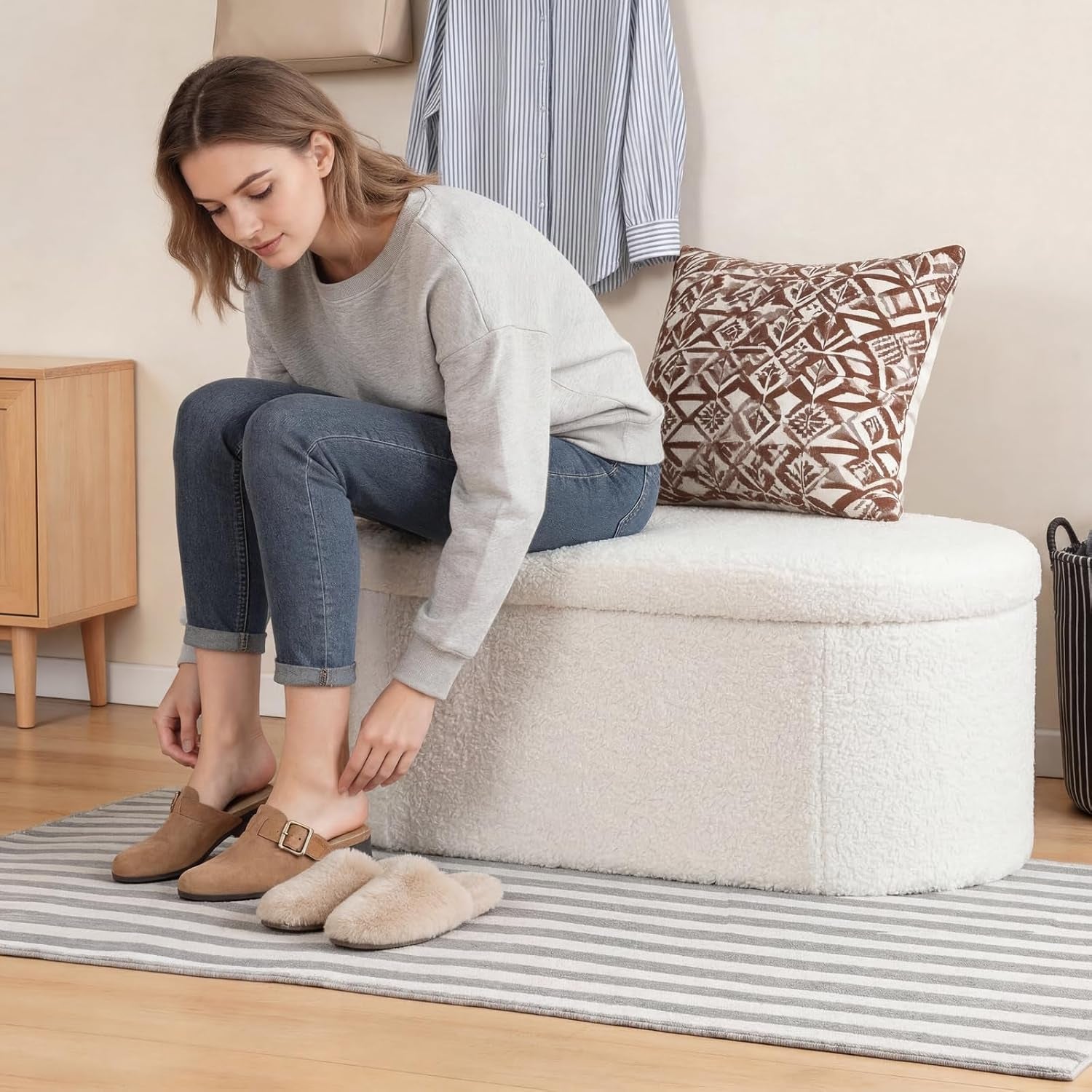 Person sitting on the closed white ottoman in an entryway using it as a shoe bench