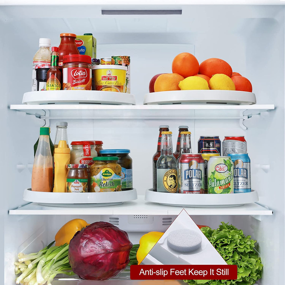 Two turntables placed on refrigerator shelves holding condiments, bottles, cans and a bowl of fruit