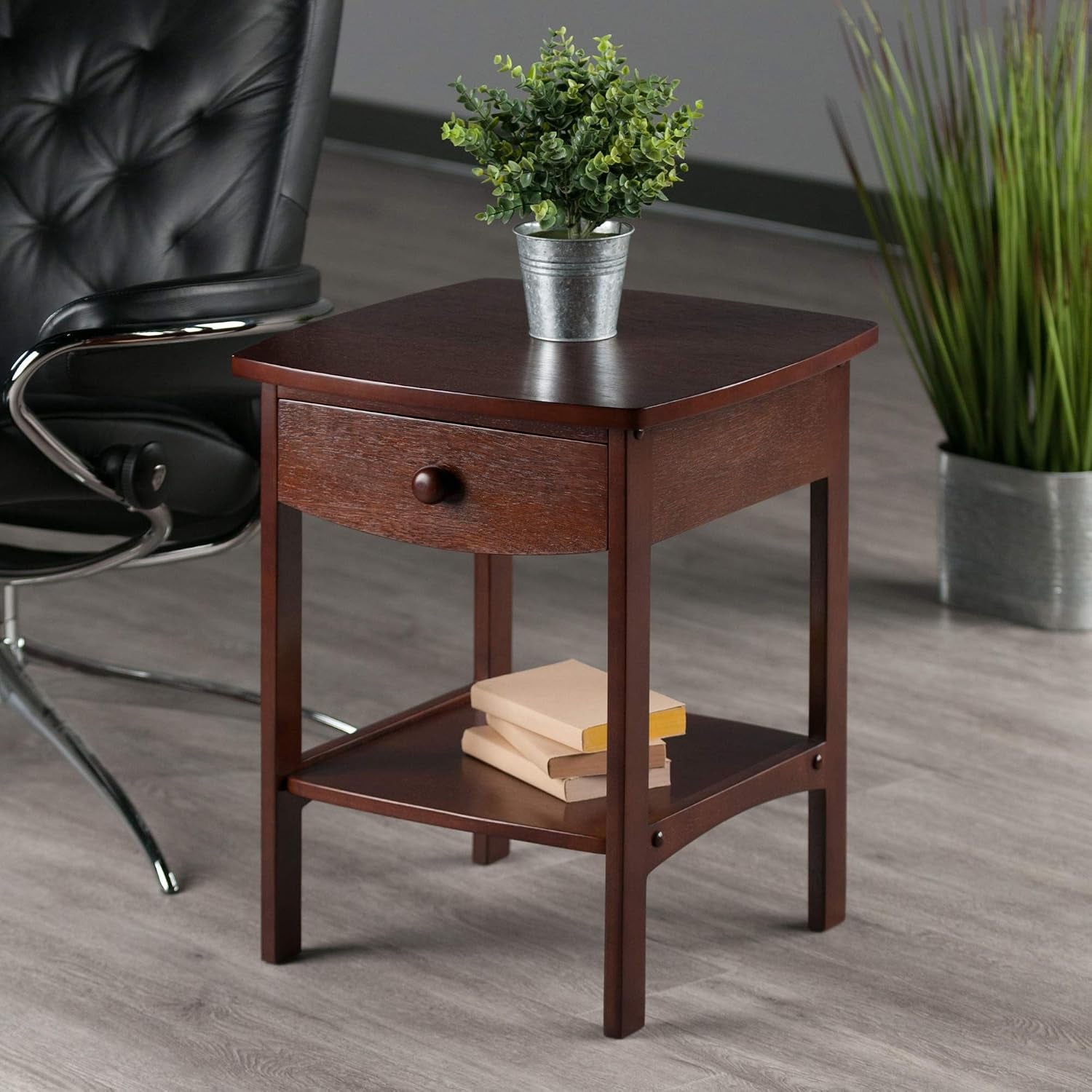 Walnut finish end table beside an office chair with a potted plant on top in a room setting