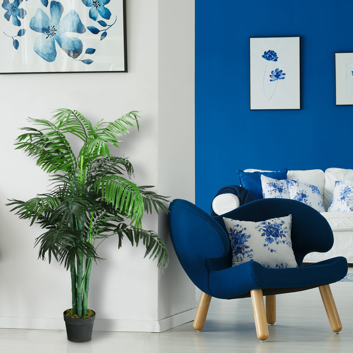 A green artificial palm in a black pot beside a blue armchair in a bright living room.
